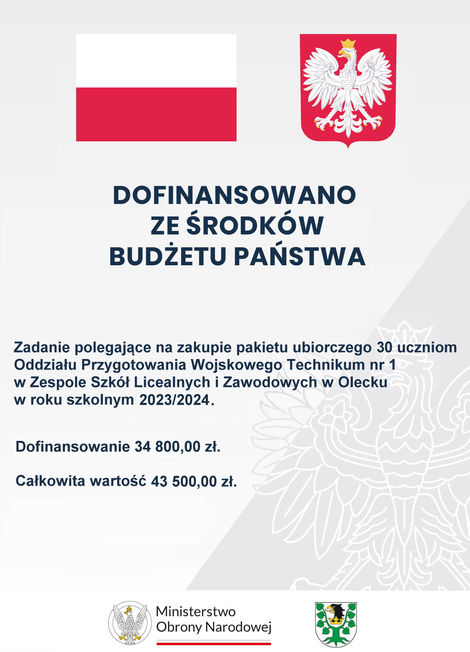 Na g&oacute;rze flaga i godło Polski. Pod nimi napisy. Dofinansowano ze środk&oacute;w budżetu państwa. Zadanie polegające na zakupie pakietu ubiorczego 30 uczniom Oddziału Przygotowania Wojskowego Technikum nr 1 w Zespole Szk&oacute;ł Licealnych i Zawodowych w Olecku w roku szkolnym 2023/2024. Dofinansowanie 34 800 zł. Całkowita wartość 43 500 zł. Na dole 2 logotypy, tj. ministerstwa i urzędu. Jeden składa się z orła po lewej i napisu po prawej: Ministerstwo Obrony Narodowej. Pod napisem barwy Polski. Drugi to herb Powiatu Oleckiego. Przedstawia on głowę orła z dziobem i koroną na szyi pomiędzy 2 konarami lipy, z kt&oacute;rych każdy ma 4 liście.